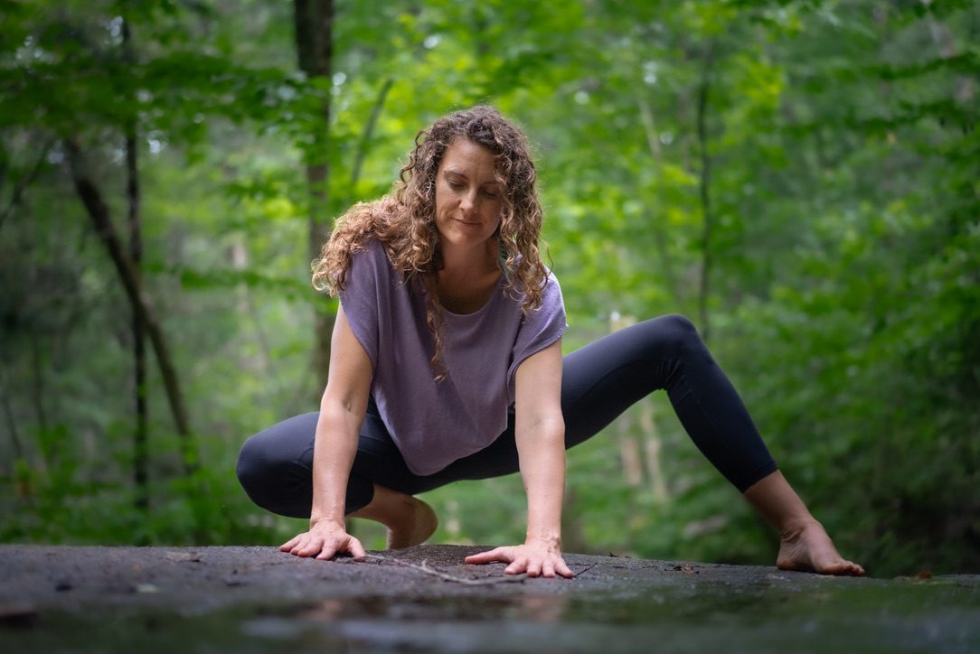 Robyn crouched on a rock in the forest